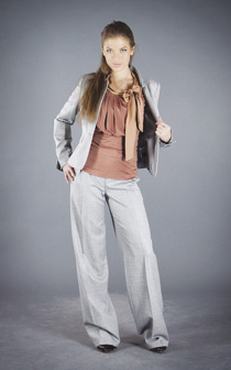 Photo of model wearing coral, bust-detailed bow blouse, gray suit jacket, and wide-leg trouser pants.