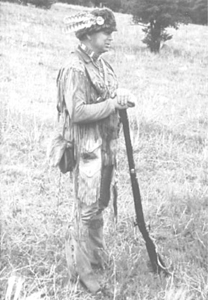 Photo of hunter wearing buckskin outfit holding a musket.