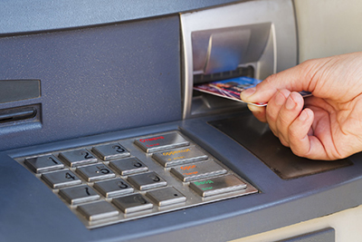 Photograph of a person inserting a card into an ATM.