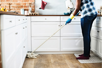 Photograph of a person mopping a kitchen floor.