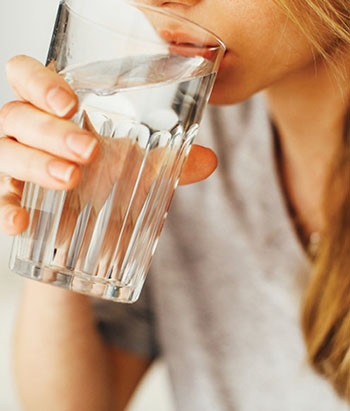 Photograph of a person drinking a glass of water.