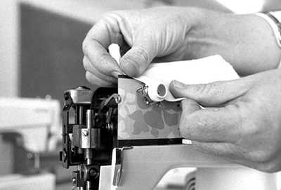 Photograph of pulling a piece of cloth soaked in solvent back and forth between the upper thread tension discs to clean.