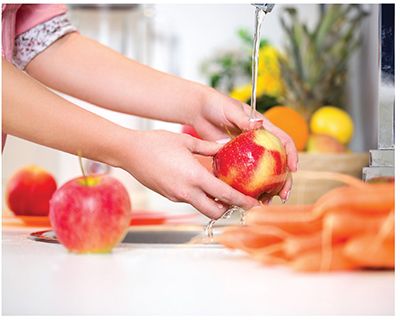 Photograph of woman hand washing an apple