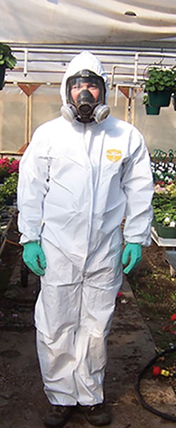Photograph of a person wearing a full-face respirator, Tyvek coveralls, and gloves.