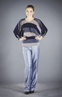 Photo of model wearing beige and blue dolman sleeved knit top and shiny blue trouser pants.