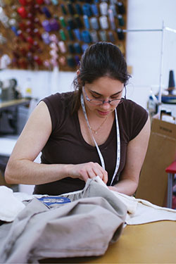 Photograph of a woman sewing a garment.