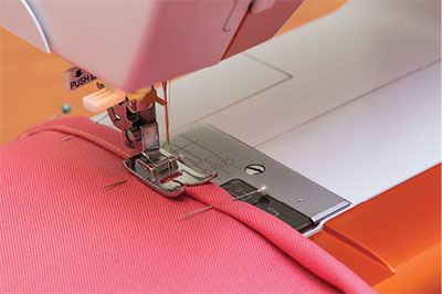 Photo of hem being sewn on a sewing machine.
