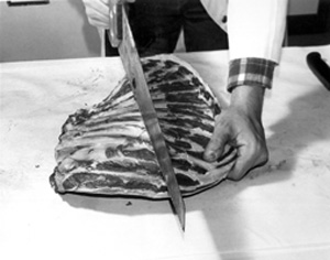 Fig. 18: Here a side of rib is being cut into plates. Plates of ribs can be barbecued whole or separated into two or three ribs per piece. Ribs can be cut into short pieces and used in stew if you prefer.