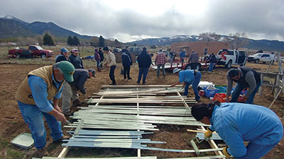 Figure 2: Photograph of people painting the wooden components of the hoop house.