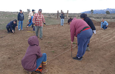 Figure 3. Photograph of people using string and rebar to mark the outline of the hoop house.