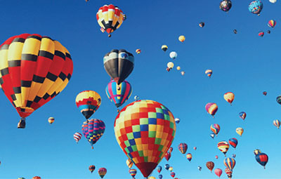 Photograph of many hot air balloons in the sky.