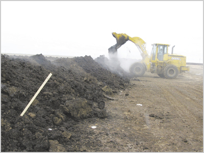 Fig. 2: Photograph of a front-end loader turning a compost pile. 
