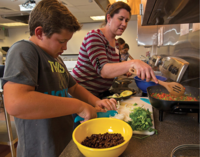 Photograph of a woman and three children preparing food.