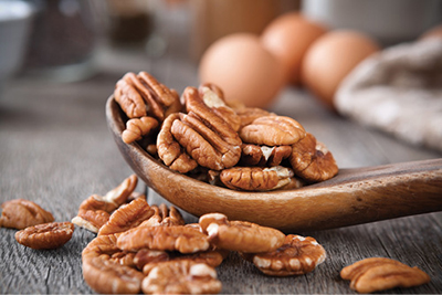 Photograph of pecans and a wooden spoon.