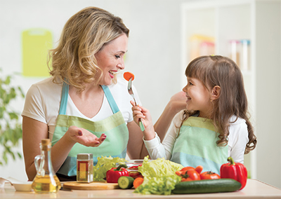 Photograph of a woman and girl eating vegetables.