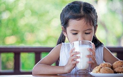 Photograph of a girl drinking a glass of milk.