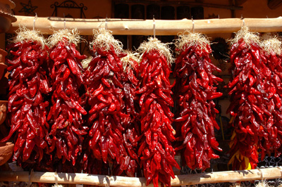 Photo of multiple red chile ristras hung up to dry in the New Mexican sun.