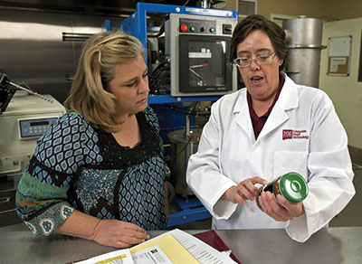 Fig. 02: Photograph of two people examining the label on a jar of salsa.