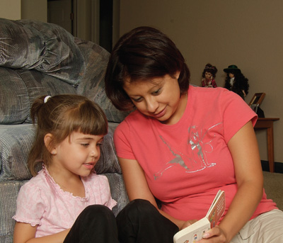 Photograph of a mother reading with her daughter./Fotografa de una madre con su hija leyendo. 