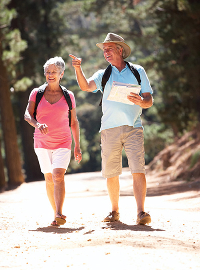 Photograph of two older adults hiking in a forest.