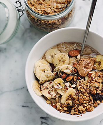 Photograph of a bowl of hot cereal with nuts and bananas.