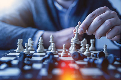 Photograph of a chessboard and a hand holding a chess piece.