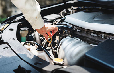 Photograph of a person checking a car’s oil.