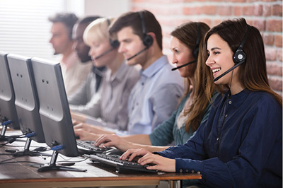 Photograph of people at computers wearing headsets.