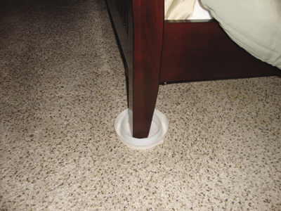 Photo of interceptor traps for bed bugs. Interceptors are placed under furniture legs. Bed bugs trying to reach a sleeping host get trapped in the wells and are not able to escape (photo by A. Romero). 