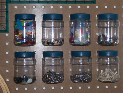 Figure 06: Photograph showing clear jars of supplies attached to a pegboard.