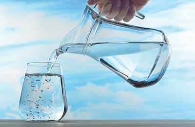 Photograph of water being poured from a pitcher into a glass.