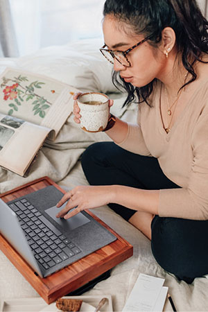 Photograph of a person holding a coffee mug while using a laptop.
