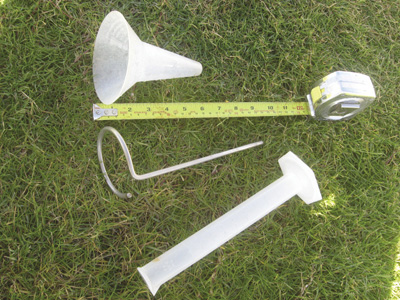 Photo of calibrated catch can, measuring tape, metal support stake, and graduated cylinder.