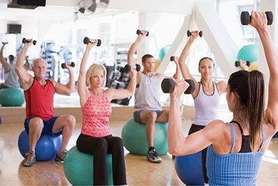 Photograph of a group of people sitting on exercise balls and lifting dumbbells.
