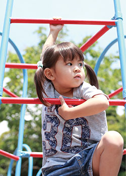 Photograph of a girl playing on a jungle gym.