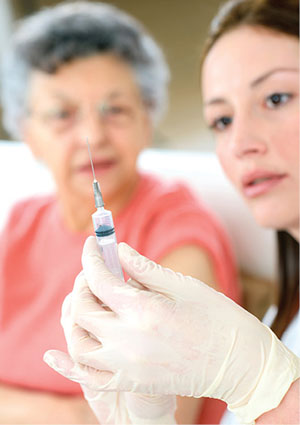 Photograph of a person holding a syringe with another person in the background.