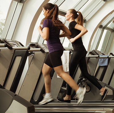 Photograph of two women running on treadmills.