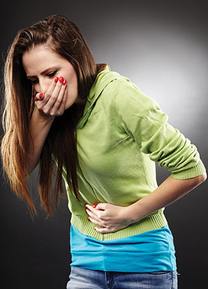 Photograph of a person covering their mouth and holding their abdomen.