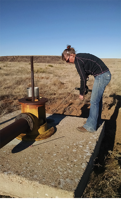 Fig. 02: Photograph of a person lowering a steel tape measure into a well.