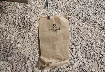 Fig. 12: Photograph of a paper bag being weighed by a small hanging scale.