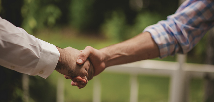 Dos personas se dan la mano en un gesto amistoso, simbolizando acuerdo o asociación.