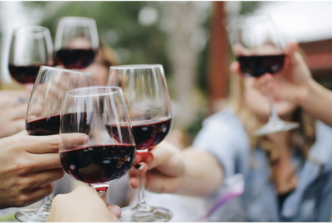 A group of people raising glasses of red wine in a toast.